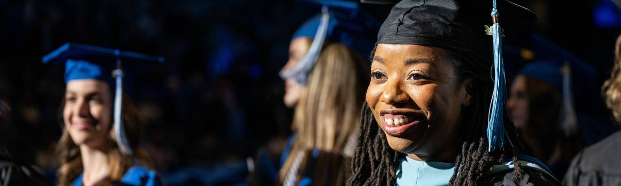 A GVSU student in cap and gown walks toward the stage during commencement